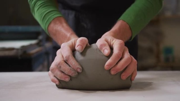 男性陶工在陶艺工作室揉捏粘土的特写镜头