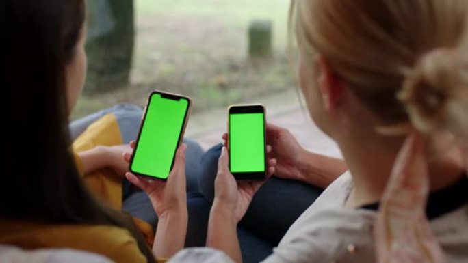 DS两名妇女在露台上使用带有色度键绿色屏幕的智能手机