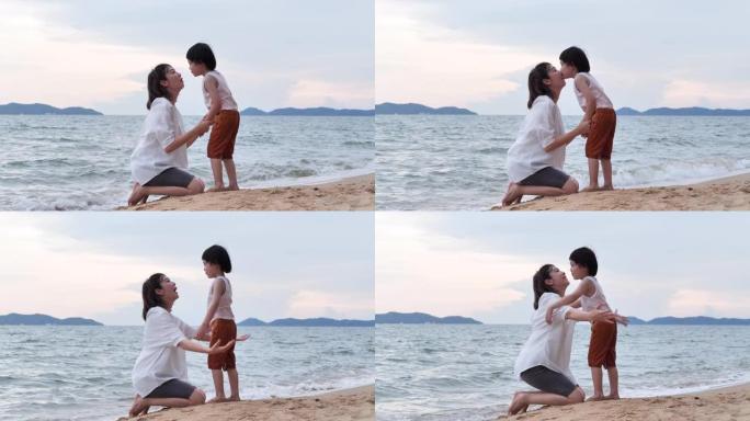 4岁的亚洲母亲和儿子的家庭花时间在沙滩上沿着日落的边缘冲浪与乐趣接吻。家庭假期快乐。母亲节2020