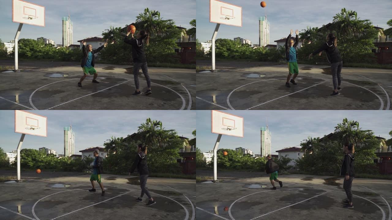 一名亚洲华裔资深男子上午与女儿在篮球场练习篮球赛