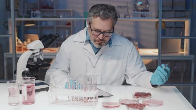 实验室外套中的成熟科学家尝试体外肉并做笔记
