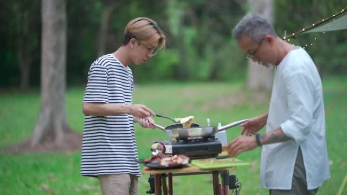 亚洲中国十几岁的男孩和他的父亲在露营帐篷为家人做饭