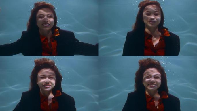 缓解压力。年轻美丽快乐的女商人在水下慢动作下看着相机的电影肖像。