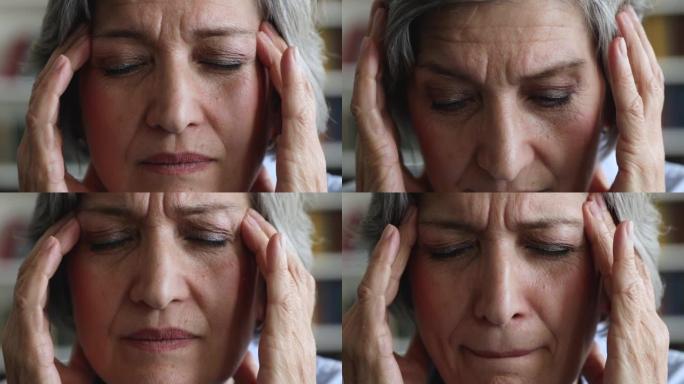 特写老年妇女擦太阳穴试图缓解强烈的头痛