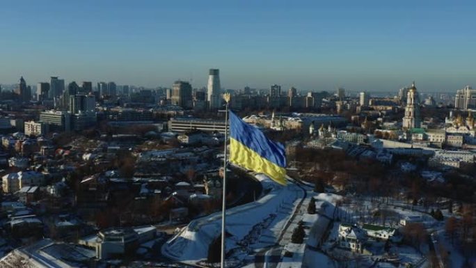 空中拍摄的大型乌克兰国旗在基辅佩切尔斯克拉夫拉附近挥舞，美丽宁静的冬季城市象征风景。