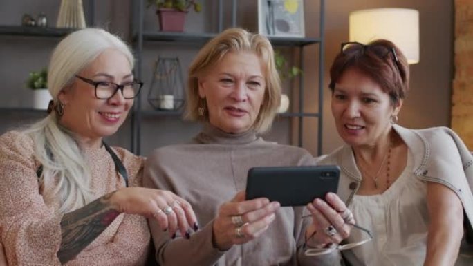 三个成年女友在智能手机上看照片时聊天