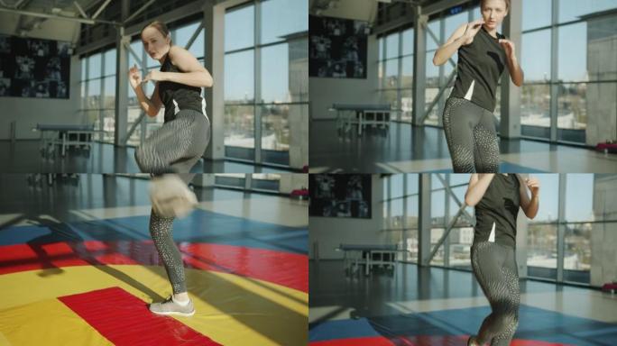 穿着运动服的年轻女士的肖像在现代健身房练习跆拳道运动