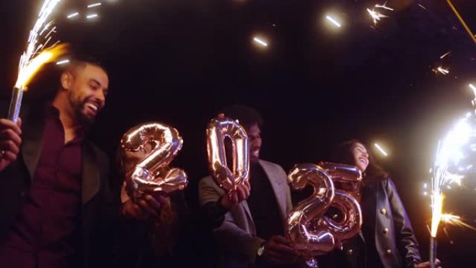 一群朋友庆祝新年拿着2025气球和烟火