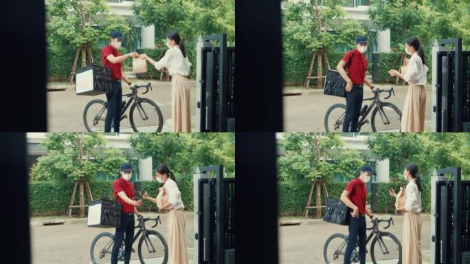 年轻的亚洲送货员，戴着红色制服的自行车戴口罩，随身携带箱盒敲门家庭在线食品纸袋给门前女士扫描家庭智能