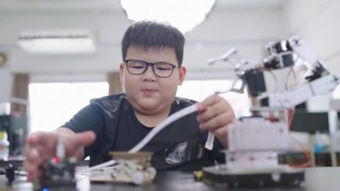在科学课上学习压力并触摸塑料管以控制机器压力的小男孩。