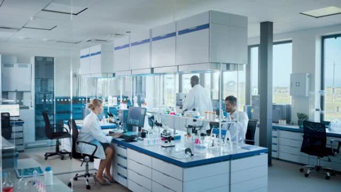 明亮的高科技医学科学实验室，由不同的专业研究科学家团队与显微镜，计算机合作。用现代设备开发药物、疫苗