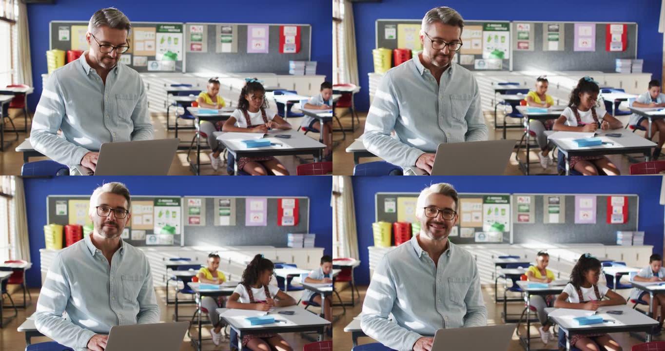快乐的高加索男老师在教室里的肖像，孩子们用笔记本电脑看着相机