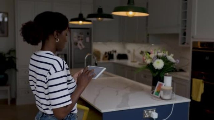 非裔美国妇女在家中使用平板电脑打开灯