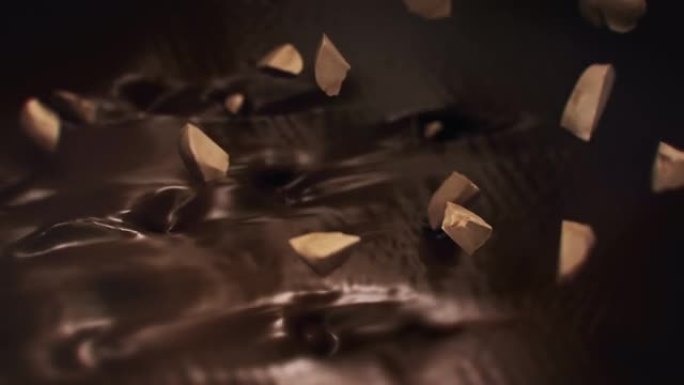 榛子碎片在4k超慢动作中溅到液体黑巧克力中