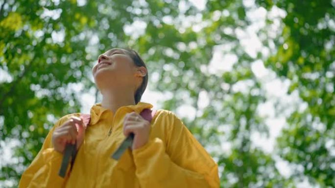 穿着黄色雨衣的女徒步旅行者和背包