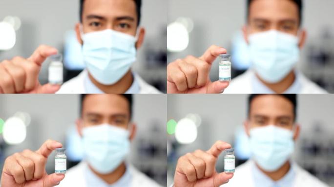 医生在模糊的背景下拿着疫苗用于病毒或covid。一位医学研究人员戴着口罩并在实验室展示了注射流感的玻