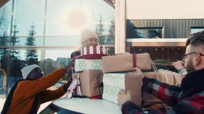 圣诞礼物递送。年轻快乐的朋友在白雪皑皑的房子的车顶上放礼物，庆祝新年慢动作。