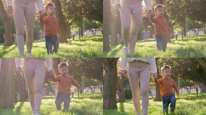 母亲牵着孩子的手，带着孩子在公园里散步，在孩子蹒跚学步的时候享受高质量的家庭时间。妈妈喜欢和春天学走