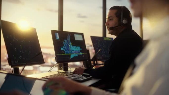 戴着耳机的男性空中交通管制员在机场塔楼通话。办公室充满了台式计算机显示屏，带有导航屏幕，飞机出发和到