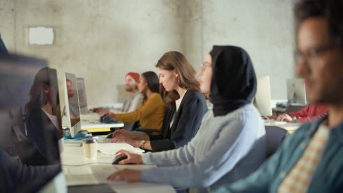 多种族的男女学生坐在大学教室里，学习计算机科学。年轻学者在大学学习计算机上的信息技术，在课堂上编写代