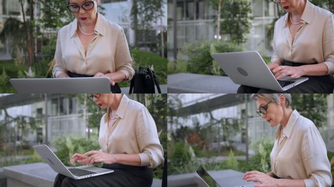 一位成功的白发女作家正坐在现代商业中心前，用笔记本电脑写一本新书，