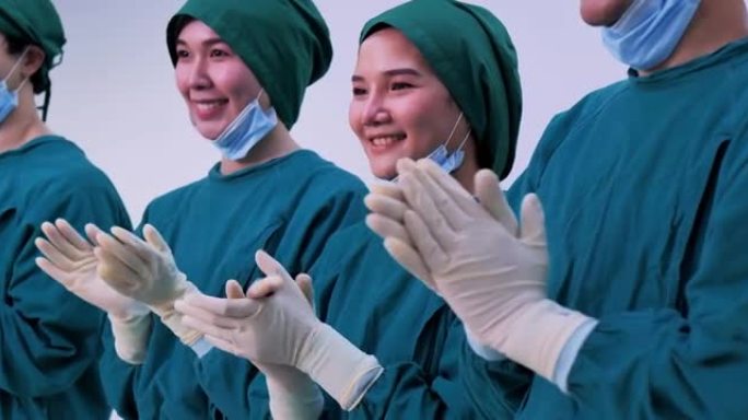 亚洲团队合作四名专业外科医生和助手鼓掌和微笑完成手术。医生团队庆祝成功拯救了手术室的生命患者。商业庆