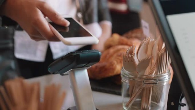 关闭使用智能手机移动汇款进行非接触式支付的客户在咖啡厅购买咖啡的妇女在餐厅享受服务