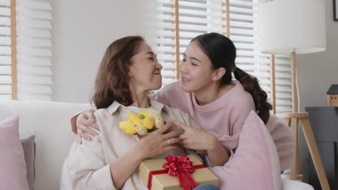 亚洲妈妈成人儿童儿童在家沙发上给拥抱亲吻礼物花