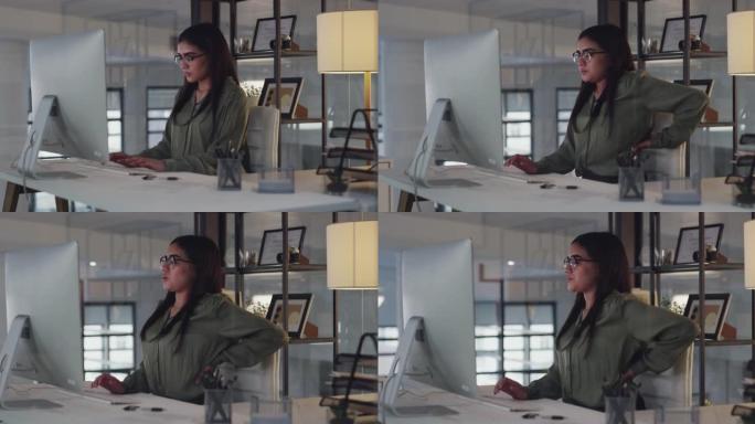 4k视频片段，一位迷人的年轻女商人独自坐在办公室里，背部疼痛