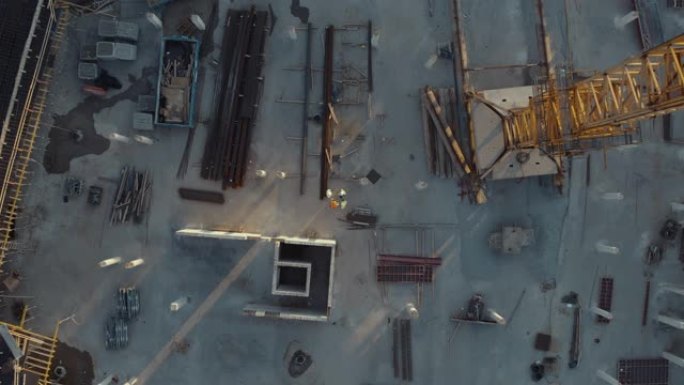 建筑工地的空中俯视图，由不同的工程师和经纬仪工作的工人组成。该地区戴着安全帽的重型机械和建筑工人。