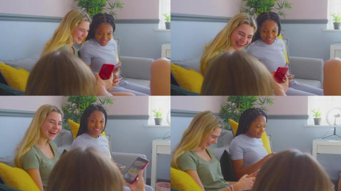 一群多元文化的少女朋友看着坐在沙发上的手机在家里的卧室里闲逛-慢动作拍摄
