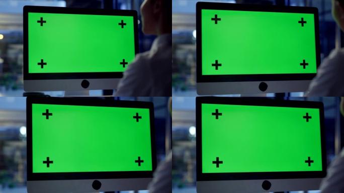 深夜办公室里有绿色chromakey复制空间的电脑屏幕。业务人员正在查看带有跟踪标记的监视器，以在线
