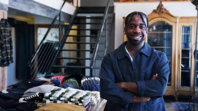 微笑的非洲裔美国男性时装店老板站在服装展示前的肖像-慢动作拍摄