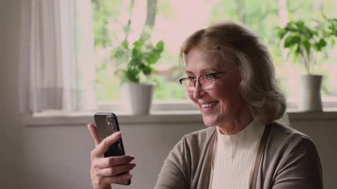 老年妇女使用智能手机浏览新闻提要，花时间上网