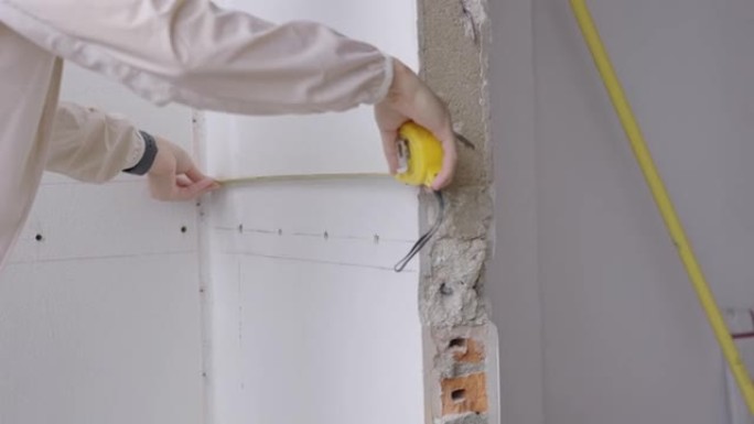 亚洲女工程师仔细测量房间墙壁的长度。