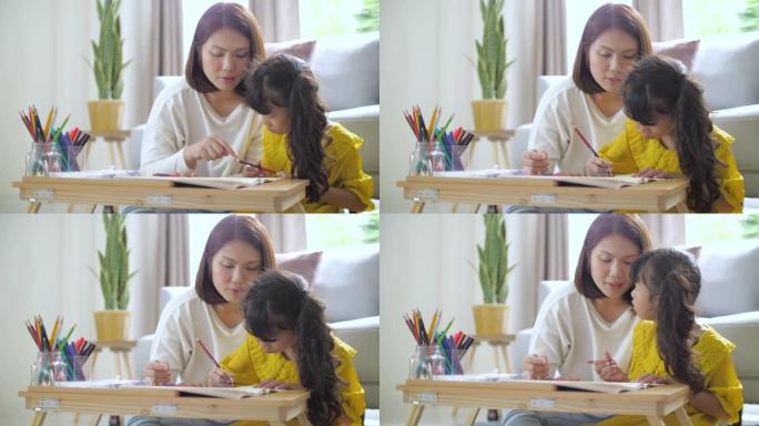 母亲在家客厅教小女孩画画