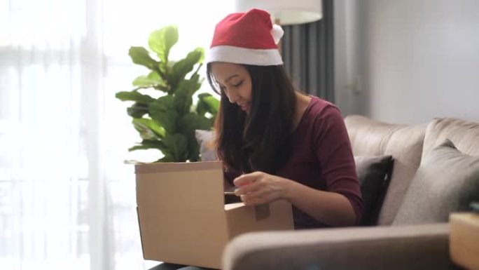 女人在圣诞节活动中在家打开在线购物盒