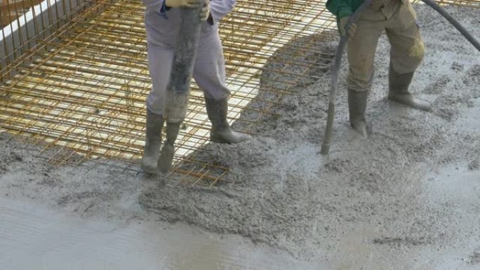 特写: 无法识别的工人团队将新鲜的砂浆倒在金属布线上。