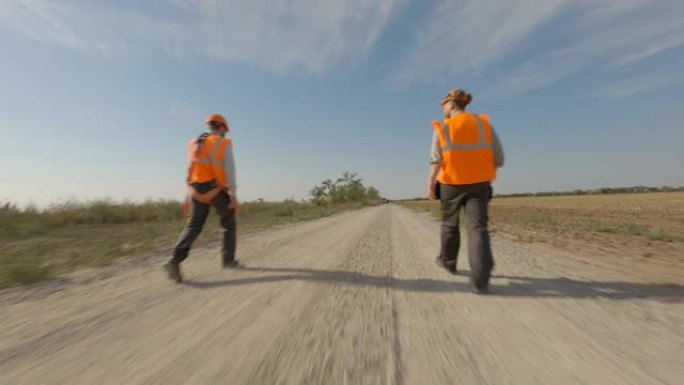 建筑商在野外风车附近的道路上行走