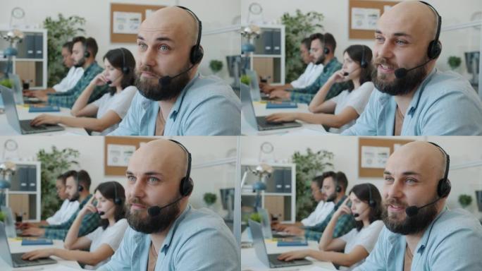 戴着耳机的有吸引力的家伙与办公室技术客户支持部门的客户交谈