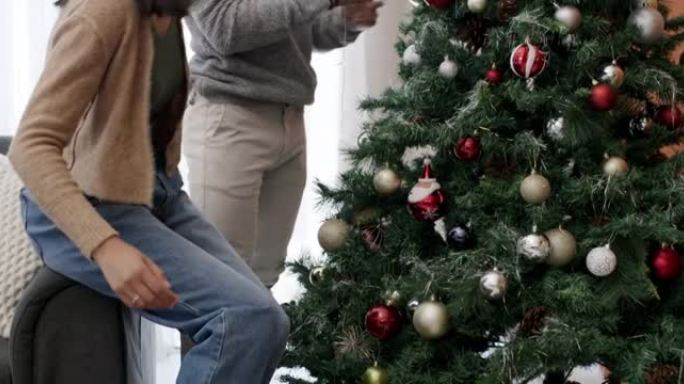 4k视频片段，一对年轻夫妇在家中堆叠礼物并一起装饰圣诞树