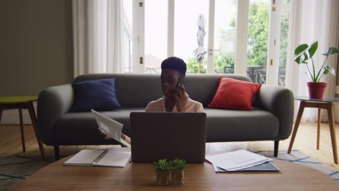 非裔美国妇女在家中工作时拿着文件在智能手机上聊天
