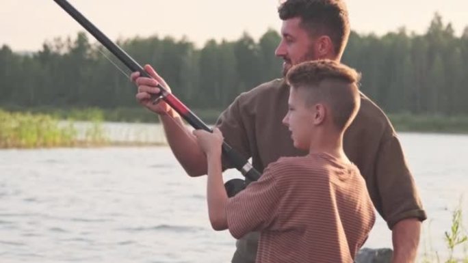 父亲教男孩钓鱼户外活动父子时刻水域