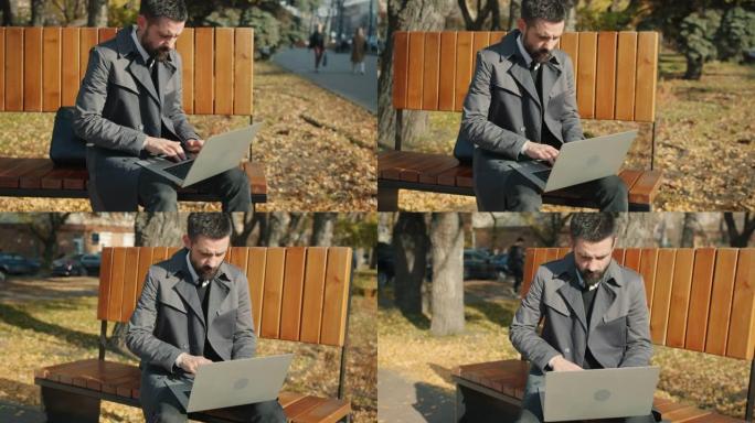 慢动作严肃的商人使用笔记本电脑坐在户外的长凳上