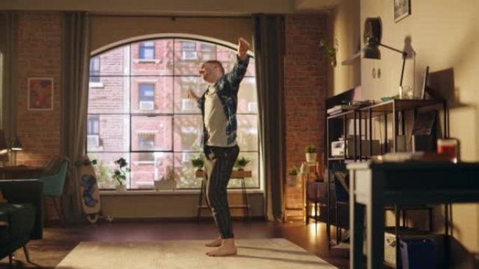 英俊时尚的年轻人穿着休闲服跳舞，在阁楼公寓里玩得开心的肖像。为社交媒体录制有趣的病毒视频。