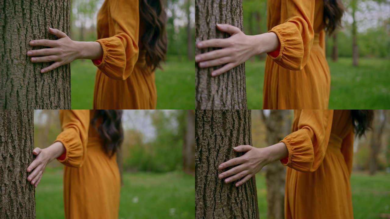 追踪，无法辨认的橙色连衣裙女性的特写镜头，以慢动作将她的手放在树皮上