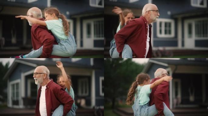 特写肖像，一个开朗的爷爷和他的孙女在户外度过，和快乐的年轻女孩玩耍。开朗的爷爷在房子前面的草坪上背着