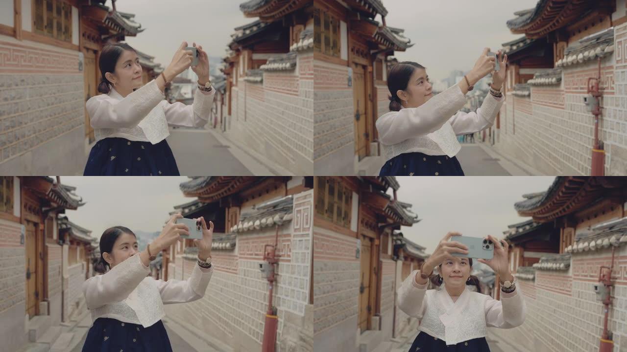 一名妇女拿着智能手机在韩国的旅游城市拍照。