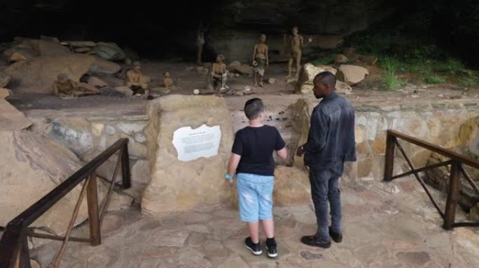 在南非夸祖鲁-纳塔尔省德拉肯斯堡巨人城堡的主洞穴里，导游向游客展示真人大小的丛林人模型场景，描绘了一