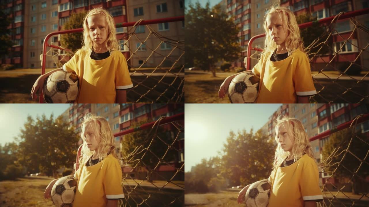 一个穿着黄色t恤的专注女孩在附近的田野里拿着足球的肖像。年轻的女子足球运动员看着镜头。运动、童年、友